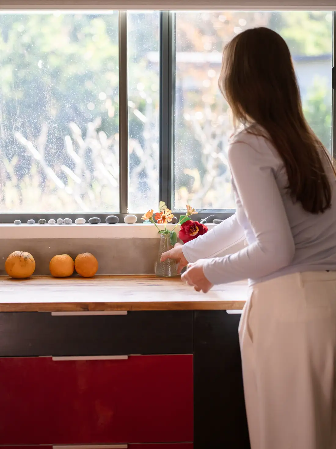 A person arranging fresh flowers in a sunlit clinic kitchen