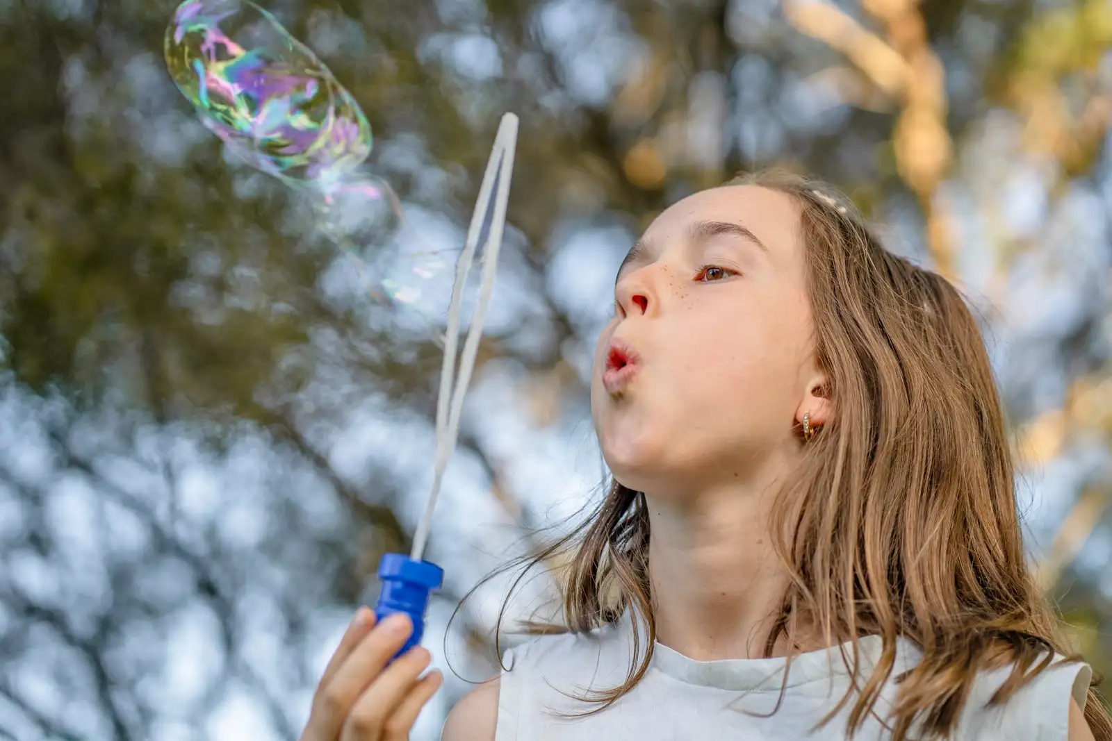 A teenager outdoors blowing bubbles in golden afternoon light