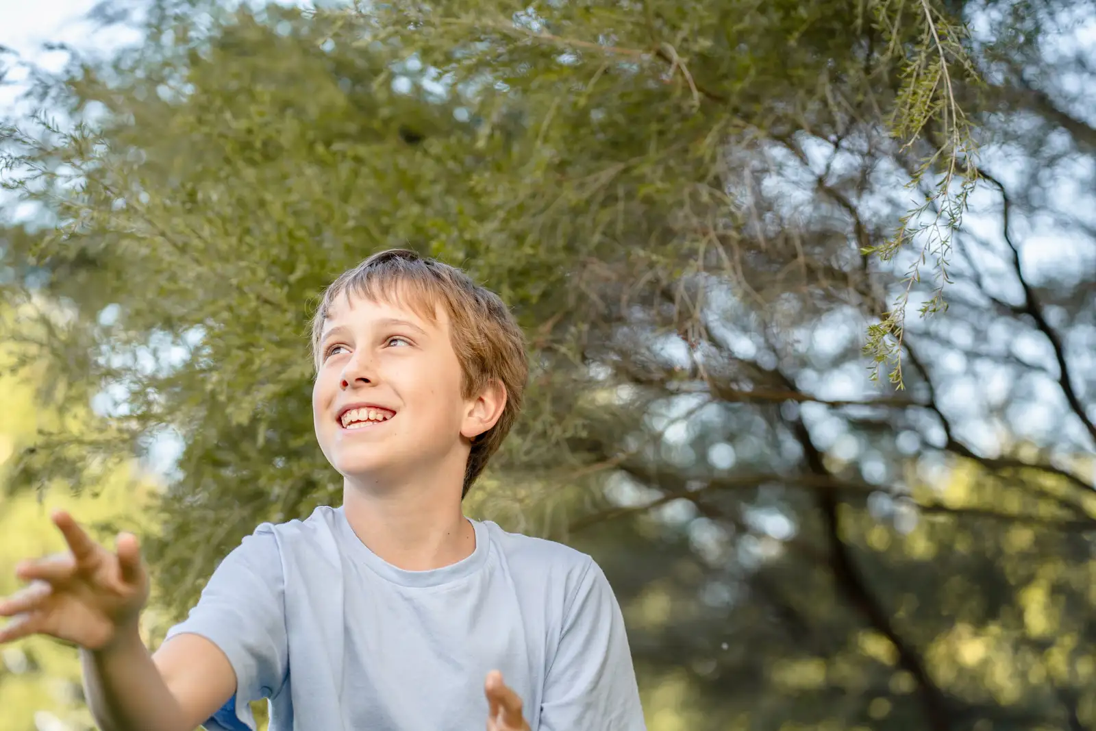 A young child smiling outdoors in warm afternoon light
