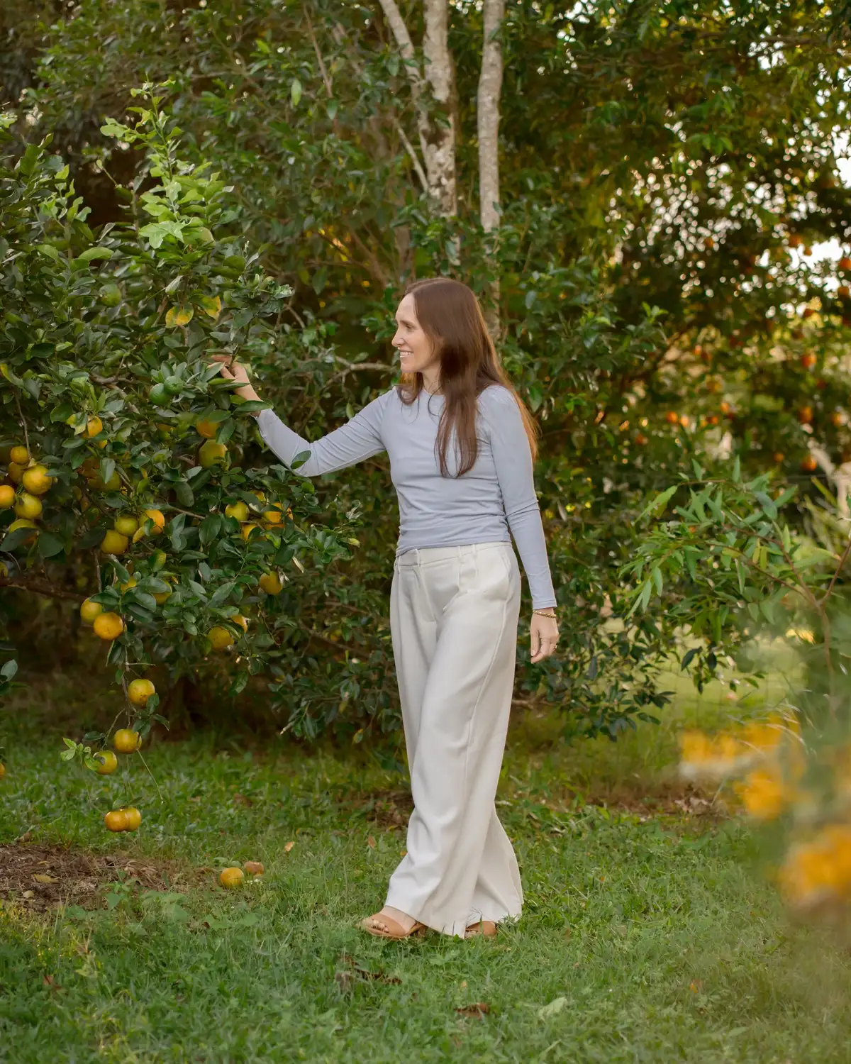 An adult standing among trees in warm afternoon light