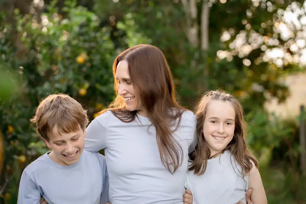 A parent and two children together among the trees at golden hour