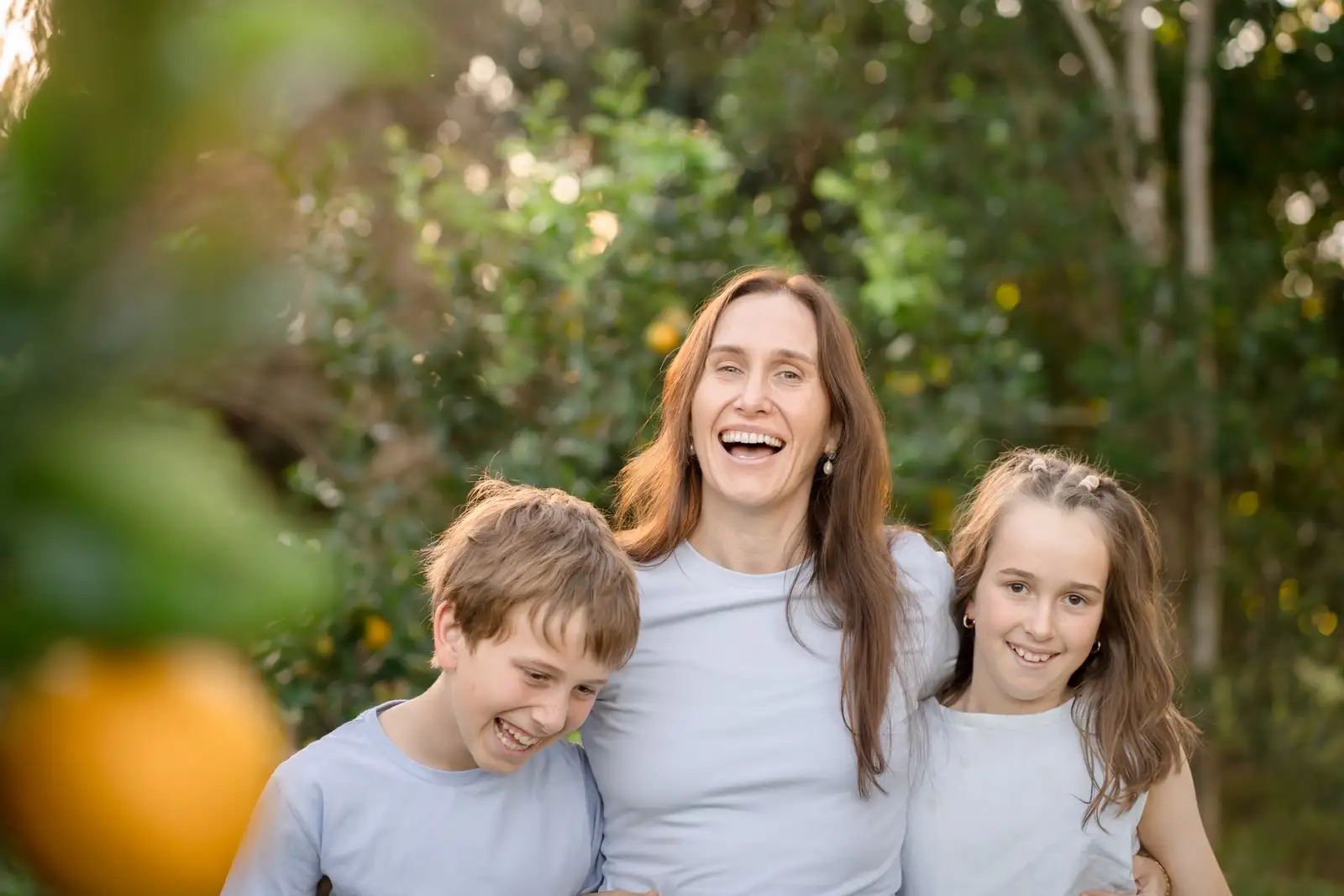 A parent with two children together outdoors at golden hour