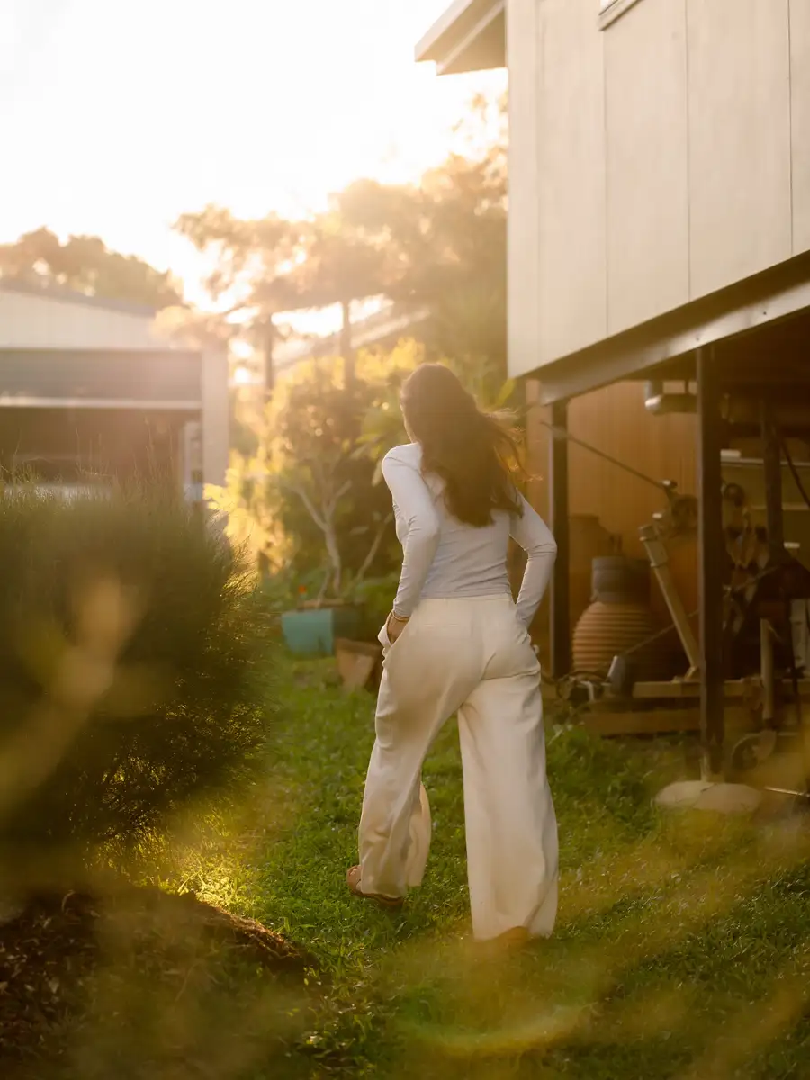 An adult walking through a garden in warm evening light