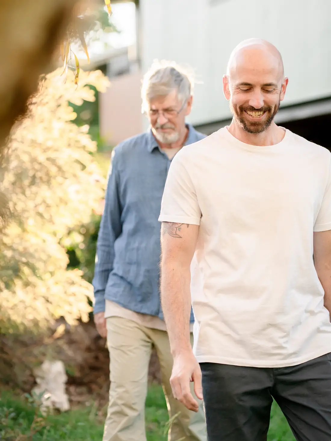 Two adults walking and talking together along a sunlit garden path