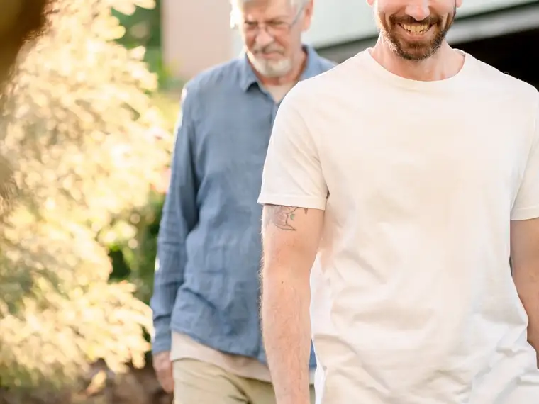 Two colleagues walking together through a sunlit garden