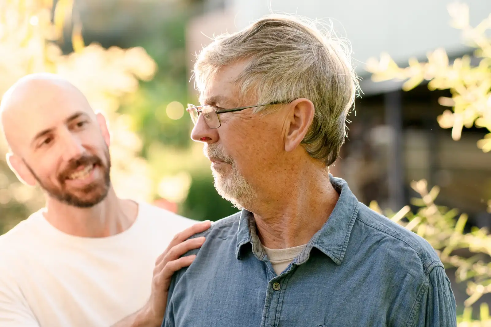 An experienced person resting a reassuring hand on someone's shoulder outdoors
