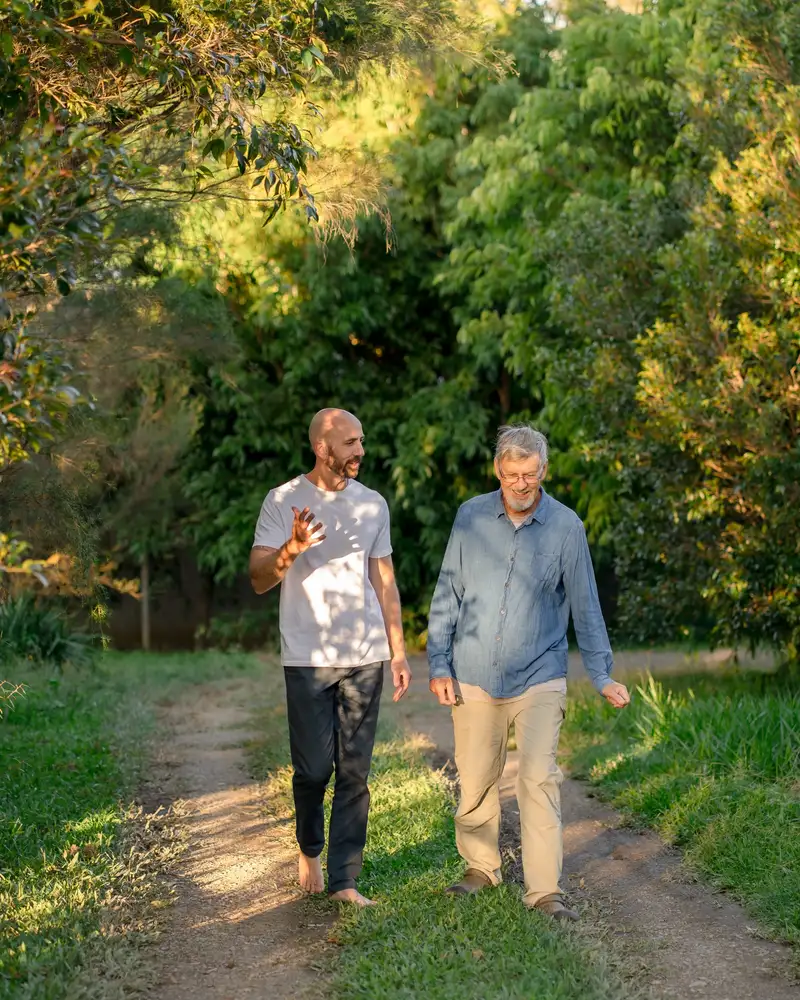 Two adults walking and talking along a sunlit garden path