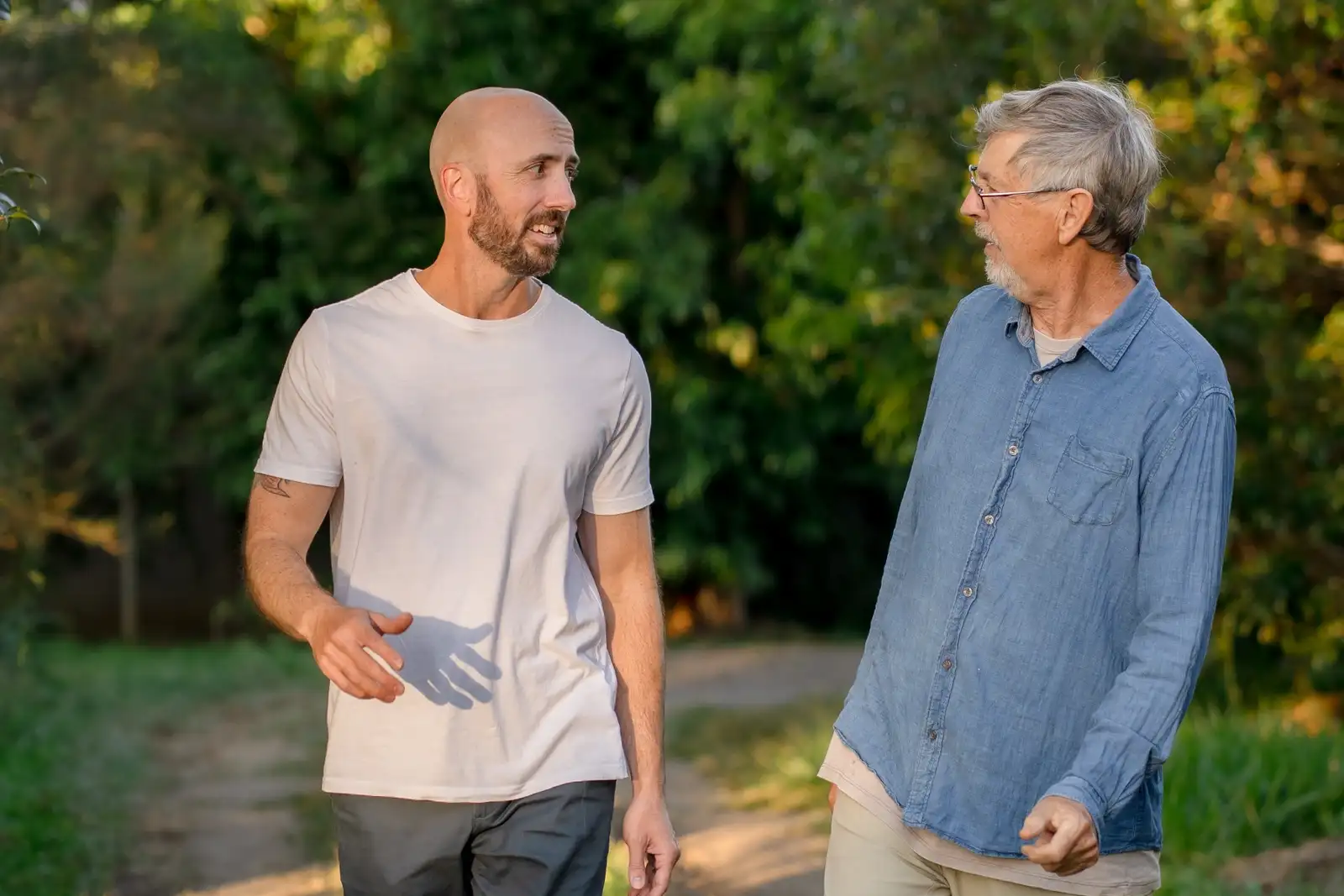 Two older adults walking together outdoors in warm afternoon light