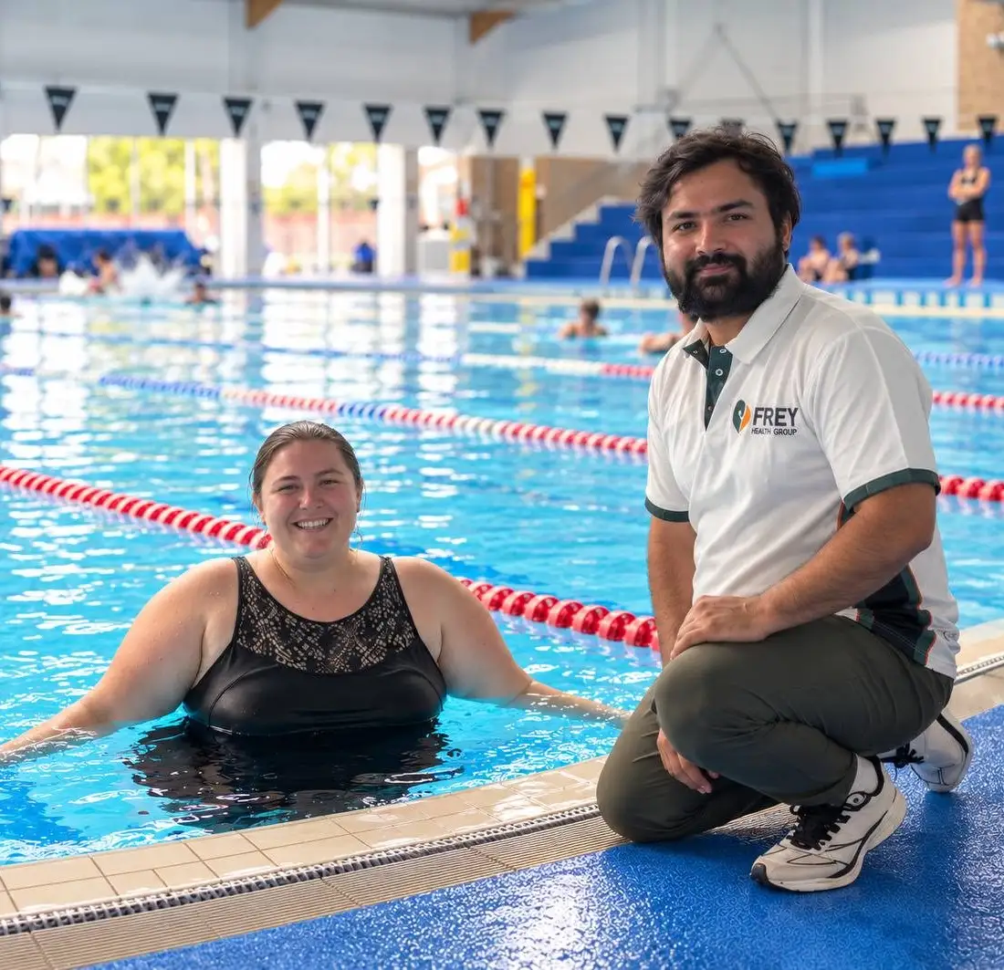 Two people smiling together at the edge of an indoor pool