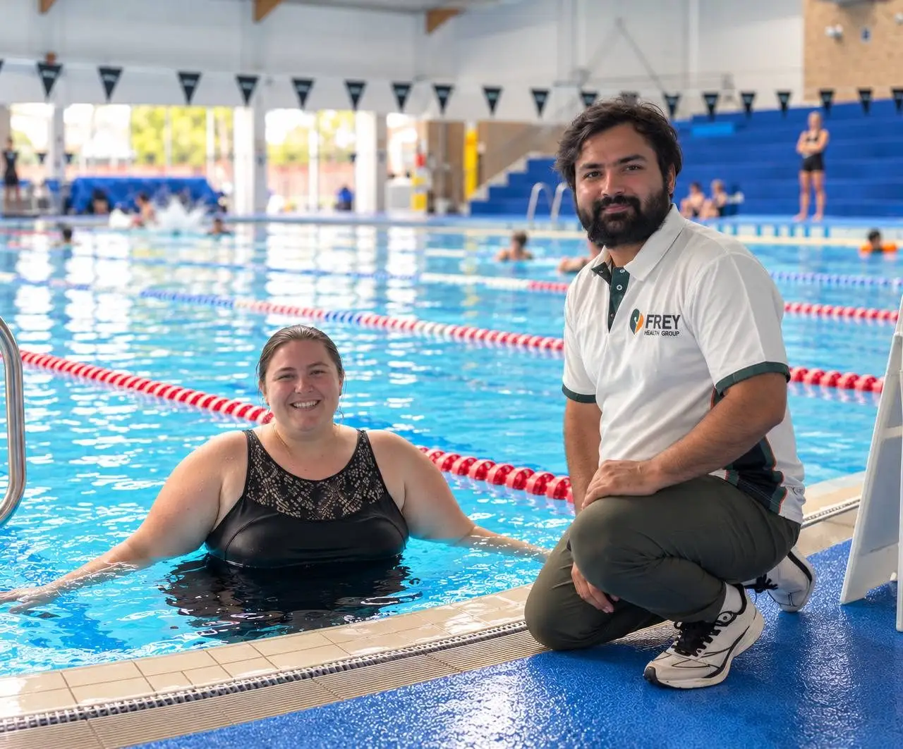 Two people smiling together at the edge of an indoor pool