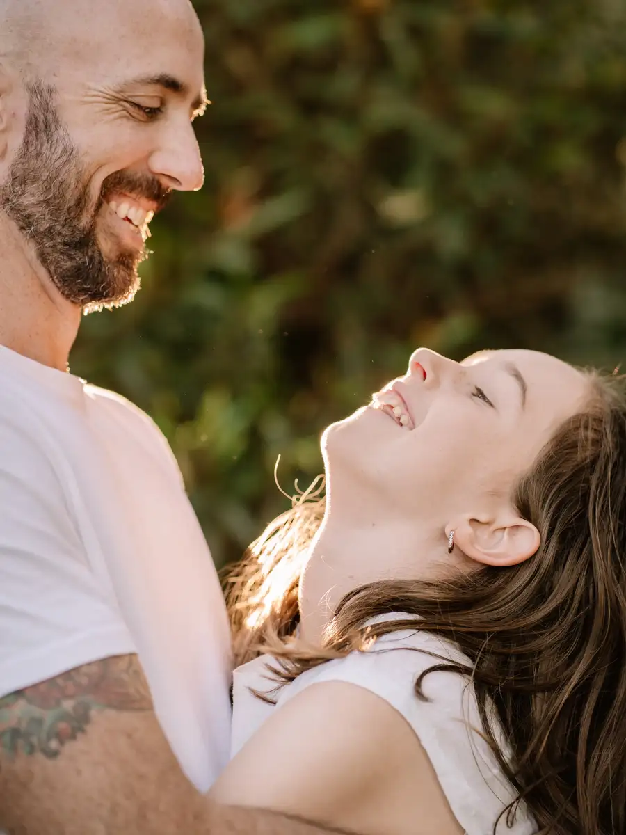 A parent and a teenager laughing together outdoors at golden hour