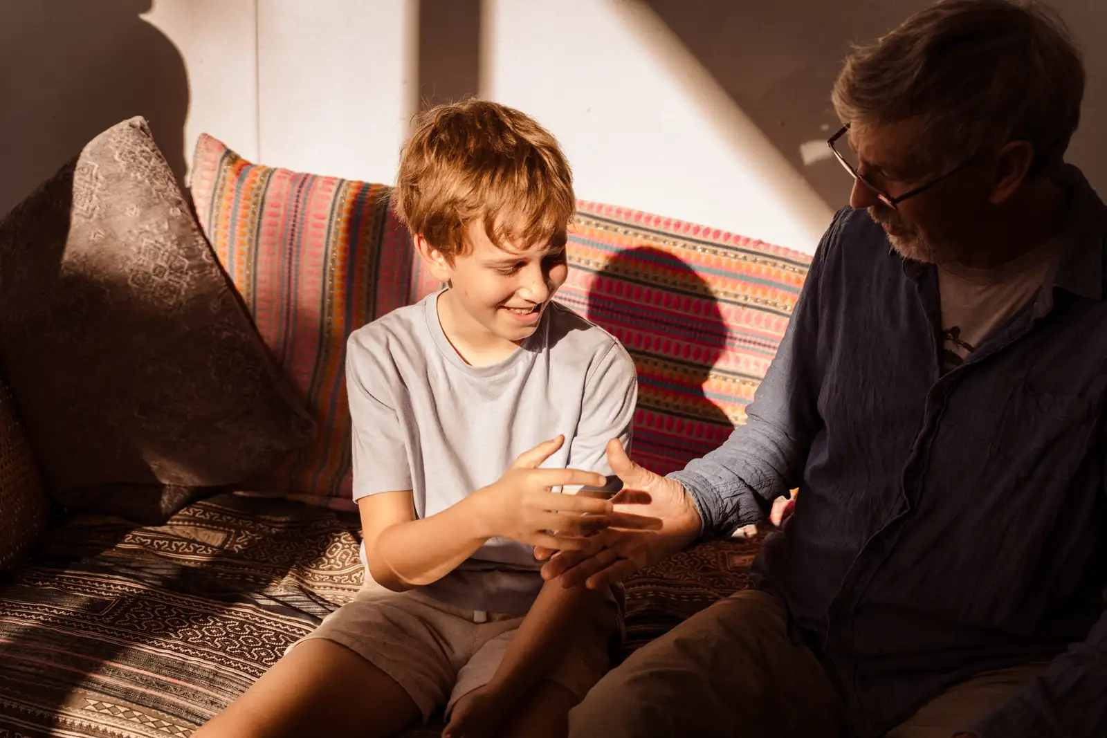 A child and an adult sharing a playful activity on a sofa