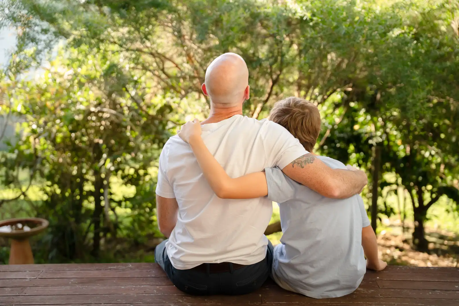 An adult and a child sitting close together outdoors