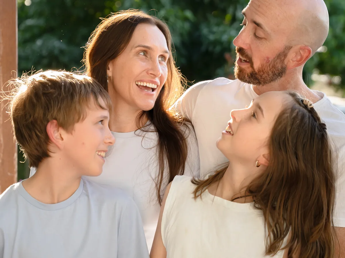 A family standing close together outdoors in warm afternoon light