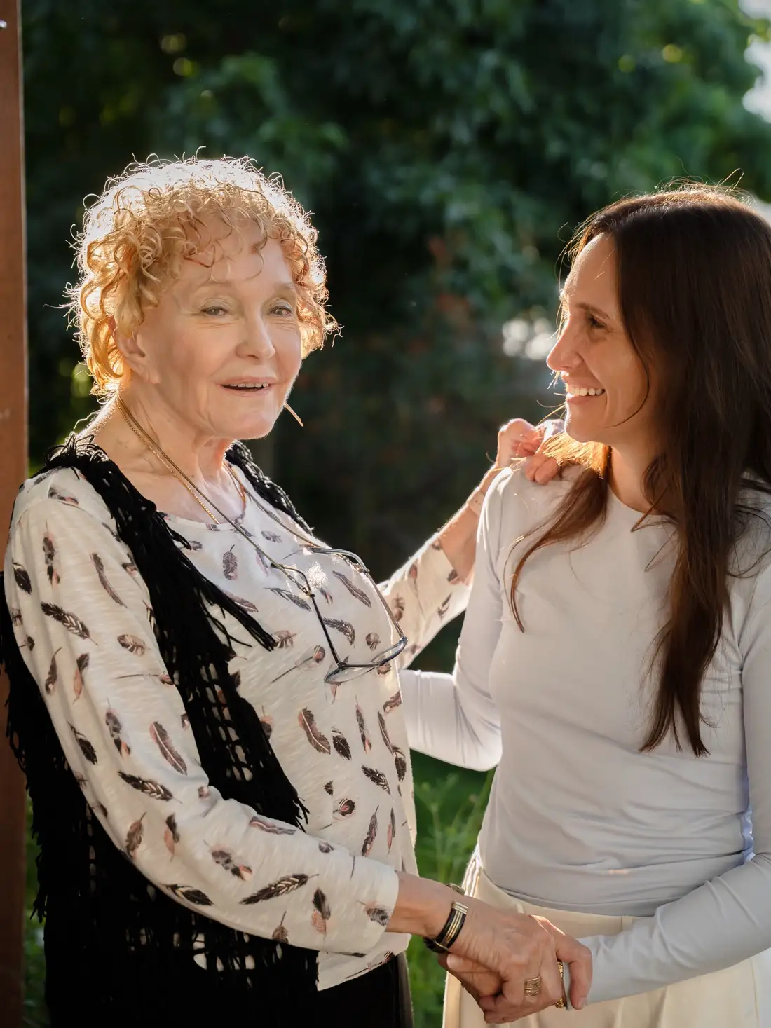An older woman and a younger woman sharing a warm moment outdoors