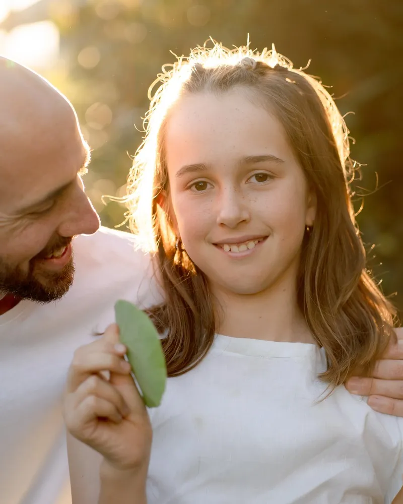A young child smiling outdoors in warm afternoon light