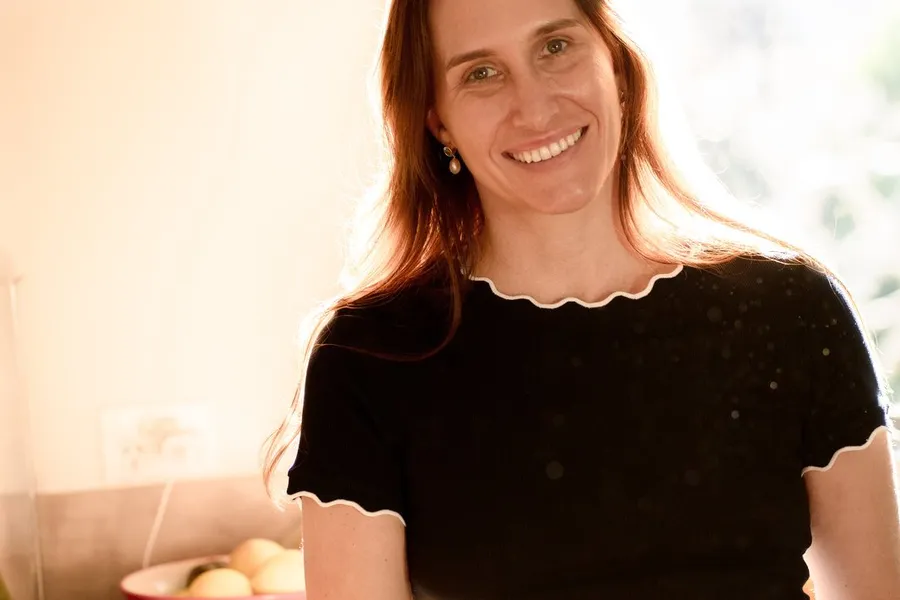 A woman at home pausing with a warm drink by the window